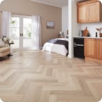 Herringbone patterned luxury vinyl flooring in a light wood tone.
